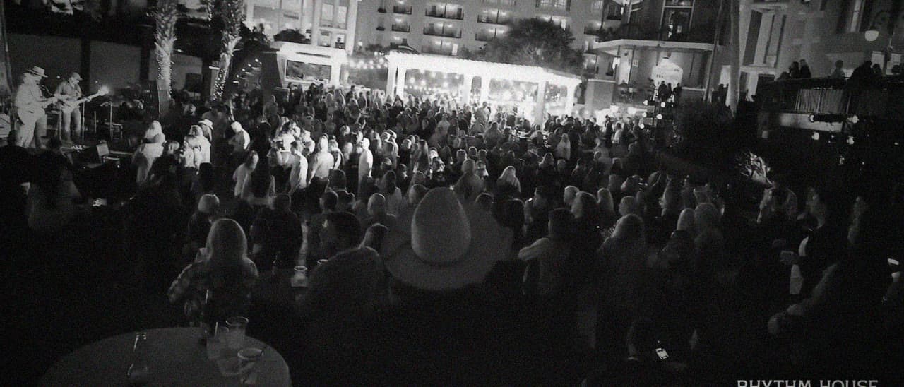 A packed courtyard crowd watching a live band at a Rhythm House night